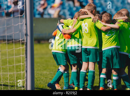 Gruppe Porträt der Jungen Fußballmannschaft. Fußball Huddle Bild. Kinder- Fußball-Mannschaft auf dem Spielfeld. Fußball-Stadion im Hintergrund. Stockfoto