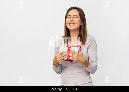 Glückliche junge Frau mit einer Geschenkbox, red ribbon auf weißem Hintergrund Stockfoto