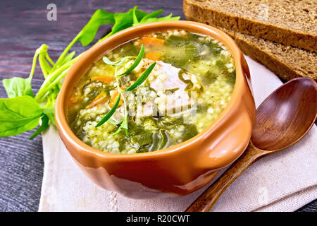 Schweinerippchen Suppe mit Couscous und Spinat in einer Schüssel auf dem Handtuch, Brot auf Holzbrett Hintergrund Stockfoto