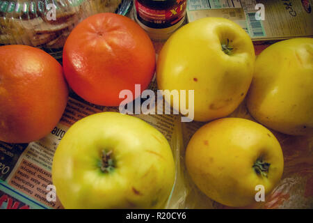 Äpfel und Orangen auf Tisch mit Zeitung. Stockfoto