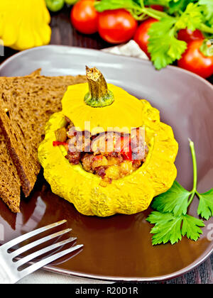Squash gelb gefüllt mit Fleisch, Tomaten und Paprika, Brot in einen braunen, Tomaten, Petersilie und Gabel auf dem Hintergrund der Holzbretter Stockfoto