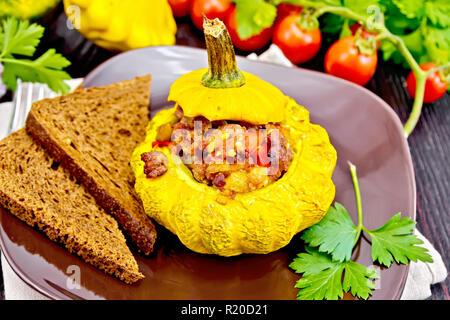 Squash gelb gefüllt mit Fleisch, Tomaten und Paprika, Brot in der Platte, Tomaten, Petersilie auf einem hölzernen Brettern Hintergrund Stockfoto