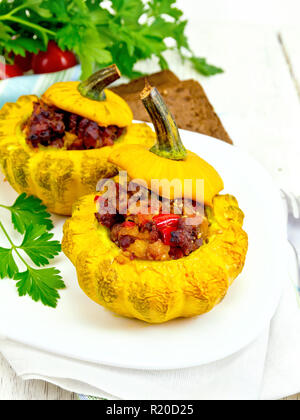 Zwei gelbe Zucchini gefüllt mit Fleisch, Tomaten und Paprika in die Schüssel, Brot, Petersilie und eine Serviette auf einem hölzernen Brettern Hintergrund Stockfoto