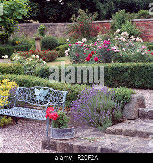 Schmiedeeisen Sitz in großen ummauerten Garten mit Rosen Stockfoto