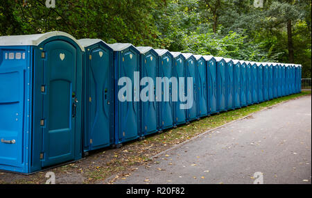 Mobile WC-Kabinen im Park. Eine Linie von chemischen Toiletten für ein Festival, gegen einen Wald Hintergrund Stockfoto