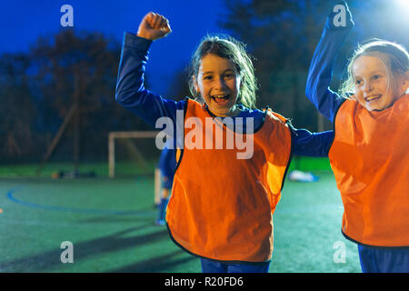 Portrait begeisterte Mädchen Fußball-Spieler jubelnd auf Feld bei Nacht Stockfoto