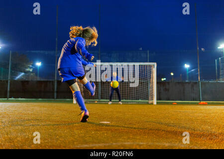 Mädchen Fußball-Spieler kicken den Ball Richtung Tor Stockfoto