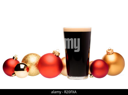 Volle pint Glas dunkles Bier oder stout Ale mit christbaumkugeln auf weißem Hintergrund Stockfoto