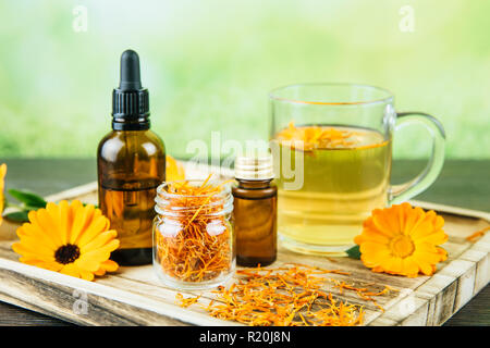 Calendula officinalis, den Pot marigold, ruddles, gemeinsame Ringelblume oder Scotch Ringelblume unterschiedliche Gesundheit Produkte auf Holz- fach, ätherisches Öl, Tinktur Stockfoto