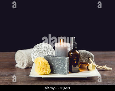 Mann Spa Entspannung Konzept. Verschiedene Day spa Produkte auf weißer Keramik Tablett auf Holztisch, dunklen schwarzen Hintergrund. Stockfoto