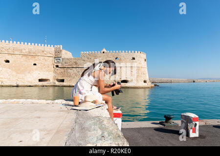 Ihnen gerne touristische Frau entspannen am Venezianischen Hafen von Heraklion. Schönes, stilvolles Mädchen auf Hafen dock genießen Urlaub Reisen nach Kreta zu sitzen. Mädchen auf Stockfoto