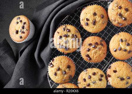 Frisch gebackene choco Chip muffins Abkühlen auf Drahtgeflecht auf dunklem Hintergrund mit Bettwäsche Handtuch, Flachbild Layout Stockfoto