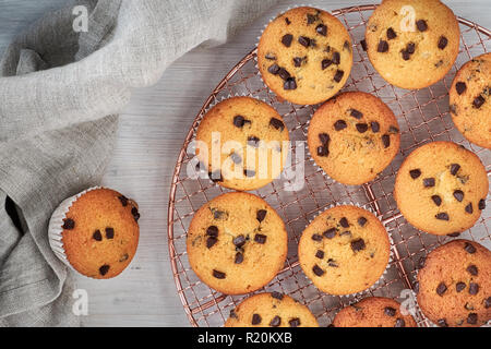 Zwölf frisch gebackene choco Chip muffins Abkühlen auf Drahtgeflecht auf Holz mit Bettwäsche Handtuch, Flachbild Layout Stockfoto