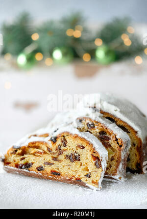 Christstollen auf Weiß festliche Hintergrund mit Tannen Zweigen und Nippes. Traditionelle deutsche Dessert für Weihnachten feiern. Stockfoto