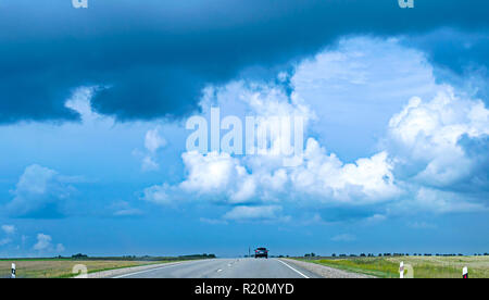 Rückansicht eines Auto Schnellfahren auf Asphalt in der Landschaft Sommer Gewitter zu entkommen. Bewölkt, stürmischen Himmel. Entlang der Route. Stockfoto