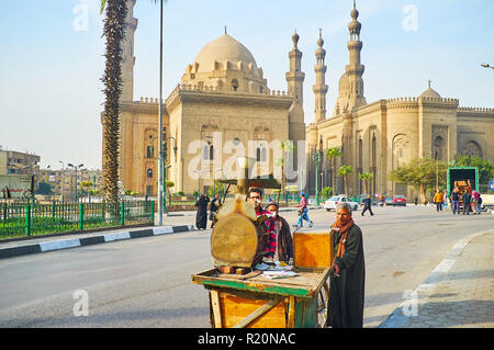 Kairo, Ägypten - Dezember 21, 2017: Kaufleute drücken Sie die Lebensmittel Warenkorb mit Ofen auf, entlang Saladin Square, mit Blick auf die Sultan Hassan und die Ro Stockfoto