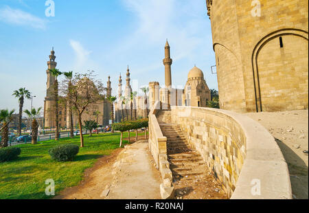 Spaziergang entlang der Halle des Bab Al-Azab Tor der Zitadelle von Saladin mit Blick auf den grünen Garten und hohen Minaretten der Moscheen in Salah El-Deen square (Sult Stockfoto