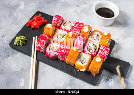 Verschiedene sushi Rollen auf die Platte an der konkreten Hintergrund serviert. Stockfoto