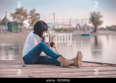 Porträt der schöne junge Frau sitzt am Fluss und ihrem Hund Basset Hound umarmen Stockfoto