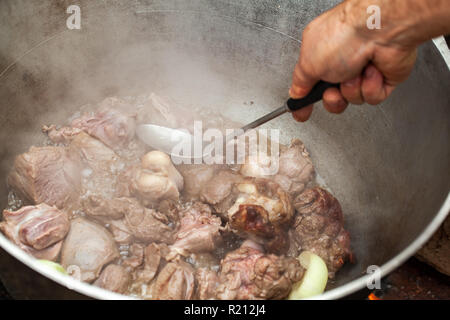 Das Mischen von gekochtem Lamm in einem Kessel. Vorbereitung der Chorba Suppe auf offenem Feuer, traditionelle Mahlzeit für viele nationale Spezialitäten, die in Europa, Afrika und Asien Stockfoto