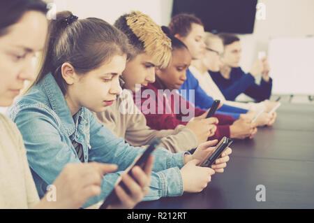 Positive russischen Mitschüler über ihre Smartphones intensiv während der Klassen Stockfoto