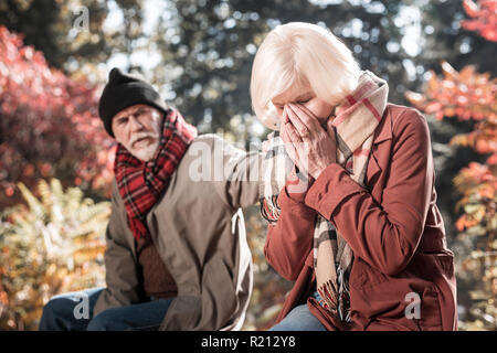 Deprimiert schreien gealterte Frau, die ihr Gesicht Stockfoto