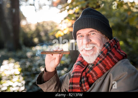 Frohe glückliche Mann hält eine große Zigarre Stockfoto