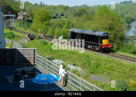 Zwei Leute beobachten Diesellok pass auf Ausdehnung der eingleisigen Bahnstrecke, England Stockfoto