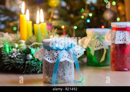 Weihnachten Geschenke auf dem Hintergrund der Zweigniederlassungen von Weihnachten Kerzen und leuchtende Girlanden. Geschenke zu Weihnachten. Glas Gläser verpackte Geschenk verpackt. In der Stockfoto