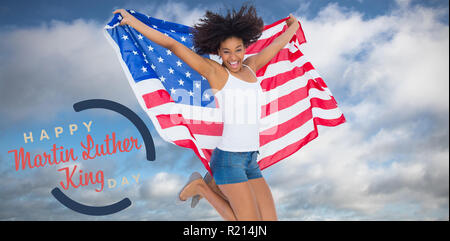 Zusammengesetztes Bild von hübschen Mädchen gehüllt in amerikanische Flagge springen und lächelt in die Kamera Stockfoto