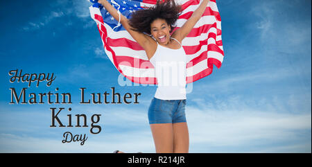 Zusammengesetztes Bild von hübschen Mädchen gehüllt in amerikanische Flagge springen und lächelt in die Kamera Stockfoto