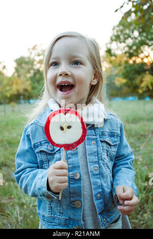 Süße kleine Mädchen mit grossen bunten Lutscher. Kind essen Süßigkeiten. Stockfoto