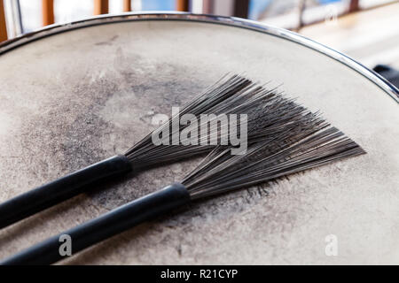 In der Nähe von ein paar schwarze Bürsten drum auf einem weißen schäbig drum. Konzept Konzert, Live Musik, Performance, musikalischen Abend in einem Restaurant Stockfoto