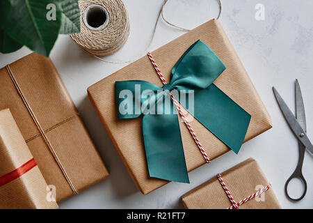 Weihnachtsgeschenke in braunes Papier und Schere mit Garn umwickelt. Ansicht von oben Stockfoto