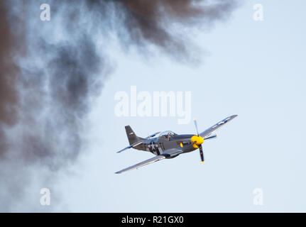 MONROE, NC (USA) - 10. November 2018: eine P-51 Mustang Fighter im Flug in der Nähe von schwarzen Rauch am Warbirds über Monroe Air Show. Stockfoto