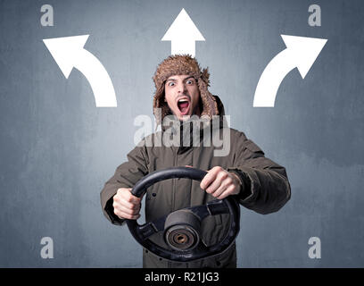 Junger Mann, schwarzes Lenkrad mit drei Pfeilen über seinem Kopf weisen in verschiedene Richtungen. Stockfoto