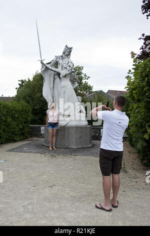 Ein paar macht ein Foto vor einer Statue von Jeanne d'Arc, an ihrem Geburtsort in Domremy-la-Pucelle, Frankreich. Stockfoto