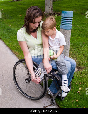 Behinderte Mutter im Rollstuhl hilft kleinen Jungen auf Schuh. © Myrleen Pearson ...... Ferguson Cate Stockfoto