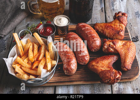 Gegrillte Chicken Wings, Würstchen, Pommes Frites, weiße und rote Sauce. Essen Bier Stockfoto