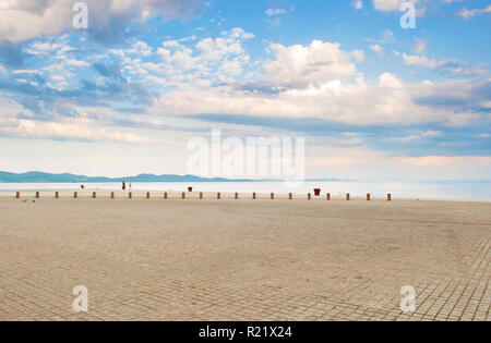 Stein Fliesen Pflaster in der Nähe der Küste vor dem Hintergrund eines Hügels und dramatische bewölkten Morgen Himmel. Zwei Frauen zahlen stehen unter Vögeln Stockfoto