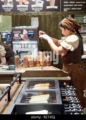 Prag, Tschechische Republik - 30. Oktober 2018, eine Person ist in der Ausarbeitung der Trdelník, eine Art von Spit Kuchen aus gewalzten Teig, ist wrapp gemacht Stockfoto