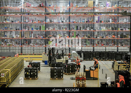 Arbeitnehmer bewegen, Gabelstapler, die vor riesigen Regalen mit Tausenden Artikeln, die bei der Erfüllung von Amazon in Swansea, in der bis zum Schwarzen Freitag. Stockfoto