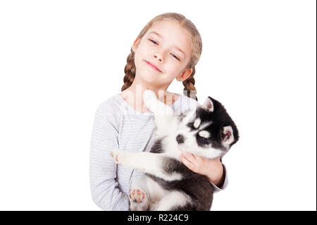 Süße kleine Mädchen umarmt einen Husky Welpe, auf einem weißen Hintergrund. Stockfoto