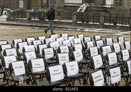 Kiew, Ukraine. 15 Nov, 2018. Ein Mann schaut auf der leeren Stühle mit angefügten Blättern mit den Namen der ukrainischen politischen Gefangenen in Russland, bei der symbolischen Leistung als "Freie Stühle auf der St. Michael's Square in Kiew, Ukraine, am 15. November 2018. Die Kundgebung richtet Regisseur Oleg Sentsov und anderen ukrainischen politischen Gefangenen in Russland, der Krim und der Konfliktzone der Osten der Ukraine zu unterstützen. Ein leerer Stuhl symbolisiert ein Autor, der sich nicht auf ein bestimmtes Ereignis in der Haft, Haft, verschwinden, lebensbedrohliche oder Mord vorhanden sein können. (Bild: Stockfoto