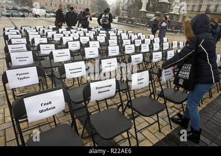 Kiew, Ukraine. 15 Nov, 2018. Ukrainische Aktivisten befestigen Sie Blätter mit den Namen der ukrainischen politischen Gefangenen in Russland zu Stühlen, bei der symbolischen Leistung als "Freie Stühle auf der St. Michael's Square in Kiew, Ukraine, am 15. November 2018. Die Kundgebung richtet Regisseur Oleg Sentsov und anderen ukrainischen politischen Gefangenen in Russland, der Krim und der Konfliktzone der Osten der Ukraine zu unterstützen. Ein leerer Stuhl symbolisiert ein Autor, der sich nicht auf ein bestimmtes Ereignis in der Haft, Haft, verschwinden, lebensbedrohliche oder Mord vorhanden sein können. (Bild: © SERG Gl Stockfoto