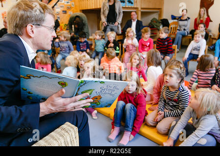 Neuwittenbek, Deutschland. 16 Nov, 2018. Daniel Günther (CDU), Ministerpräsident von Schleswig-Holstein, sitzt mit einem Buch vor der Kinder in der Tagesstätte "Lütt Wittenbeker'. Die allgemein Vorlesen Tag findet zum 15. Mal im Jahr 2018 und dieses Mal unter dem Motto "Natur und Umwelt" statt. Credit: Frank Molter/dpa/Alamy leben Nachrichten Stockfoto