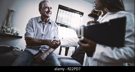 Low Angle View von Therapeuten und ältere männliche Patienten die Hände schütteln Stockfoto