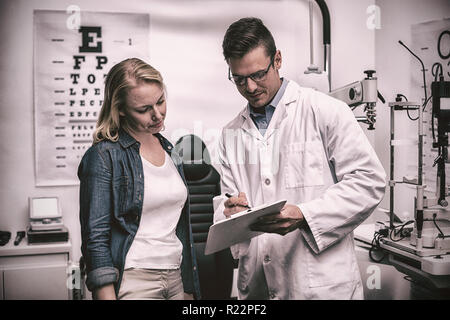Optiker diskutieren Auge Testbericht mit Patientin Stockfoto