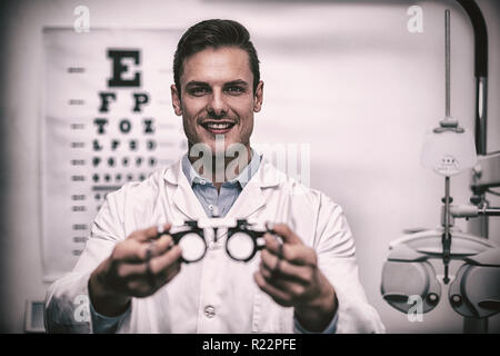 Lächelnd hält Messbrille Augenarzt Stockfoto