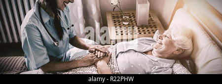 Krankenschwester, die Interaktion mit älteren Frau auf Bett Stockfoto